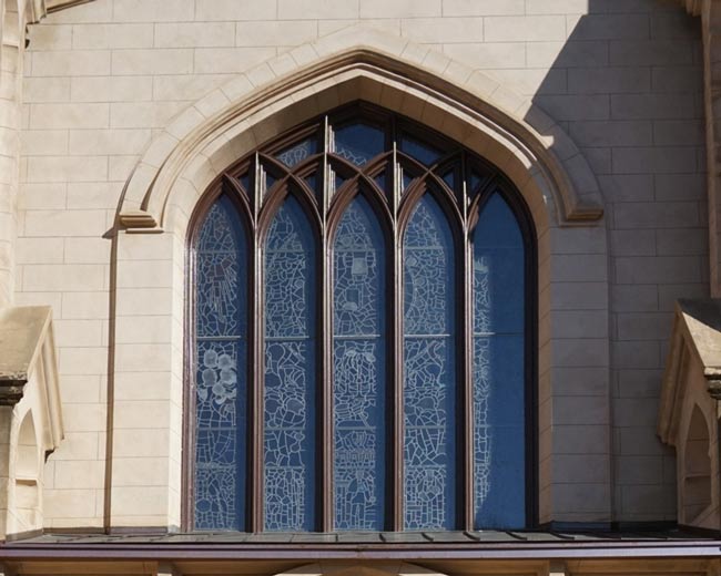 View of exterior of building. Stained glass window design is visible through clear glass protective exterior layer